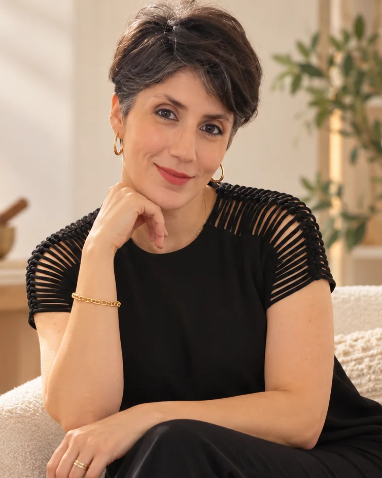 Dona Maria, smiling, seated in a calm room with candles and plants